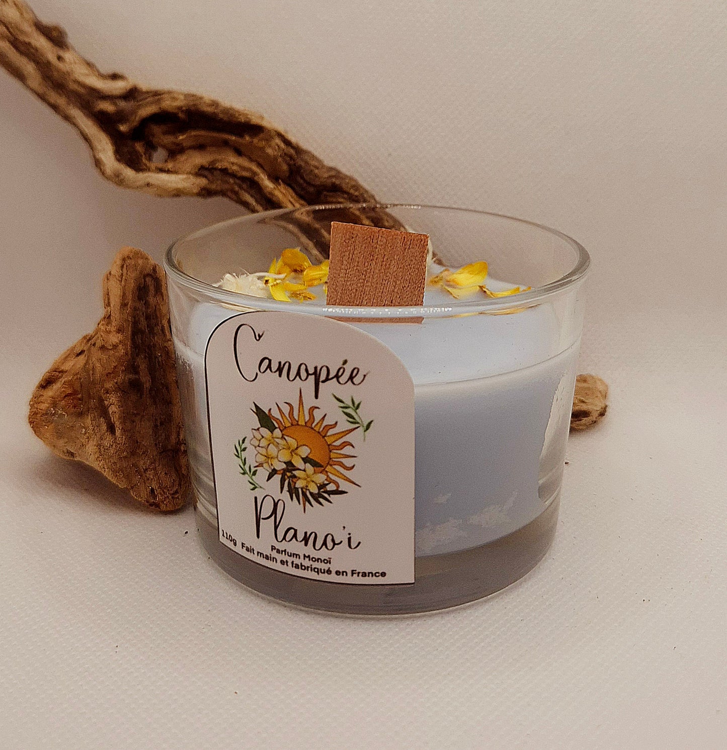 Bougie artisanale Canopée Plano’i au parfum exotique de monoï, cire bleu clair décorée de fleurs séchées, mèche en bois, faite à la main en France dans un pot en verre transparent.